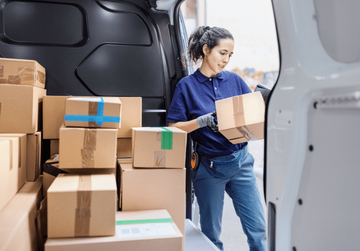 A delivery driver examines a package shipping label outside of a delivery van. 