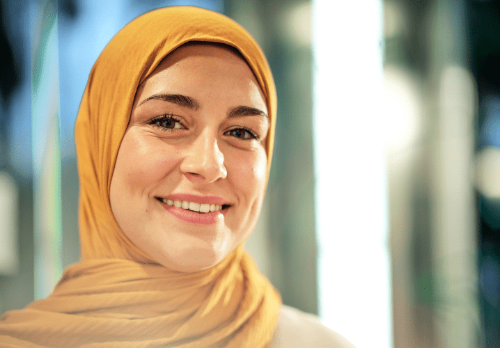 Une femme en hijab jaune sourit.